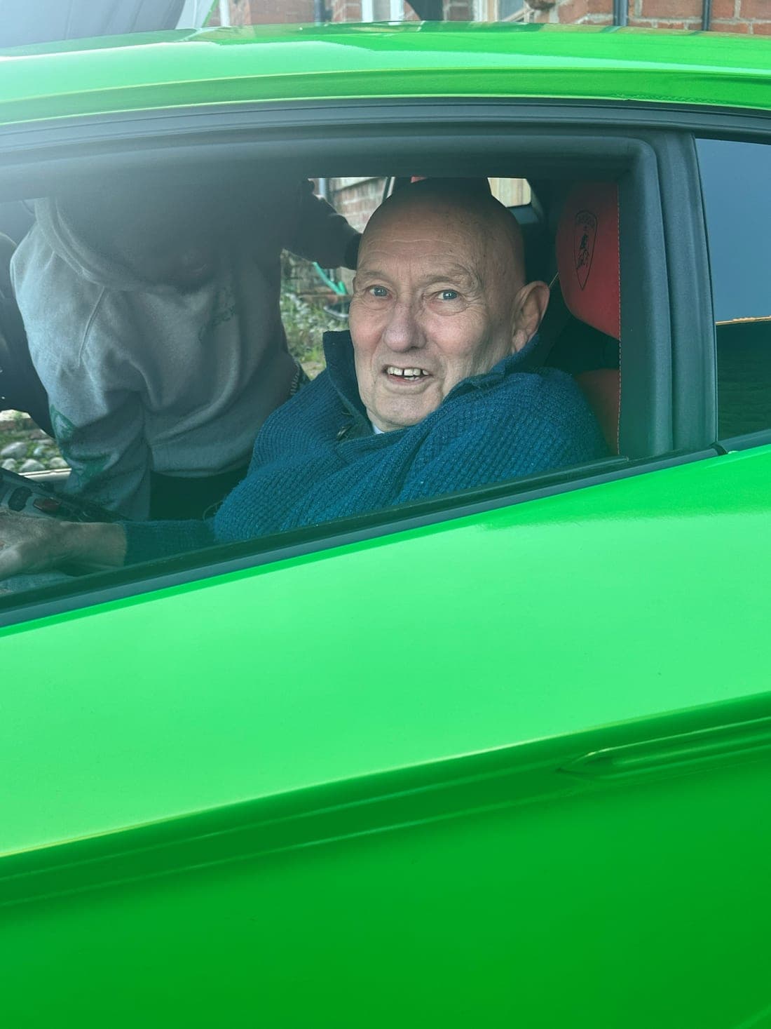 A Spire Homecare live-in care client smiling from the driving seat of a green Lamborghini