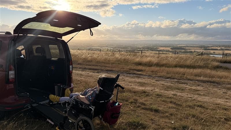 A Spire Homecare client enjoying a countryside view from an accessible vehicle